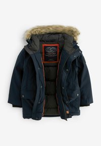 Giacca imbottita blu navy con cappuccio in pelliccia sintetica, dettagli arancioni, chiusure con zip e bottoni a pressione, tasche laterali e fodera trapuntata.