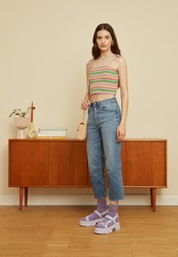 Top cropped em crochet com riscas em rosa, verde e roxo. Jeans de cintura alta em denim de lavagem clara. Sapatos chunky de plataforma em lavanda. Bolsa de trama.