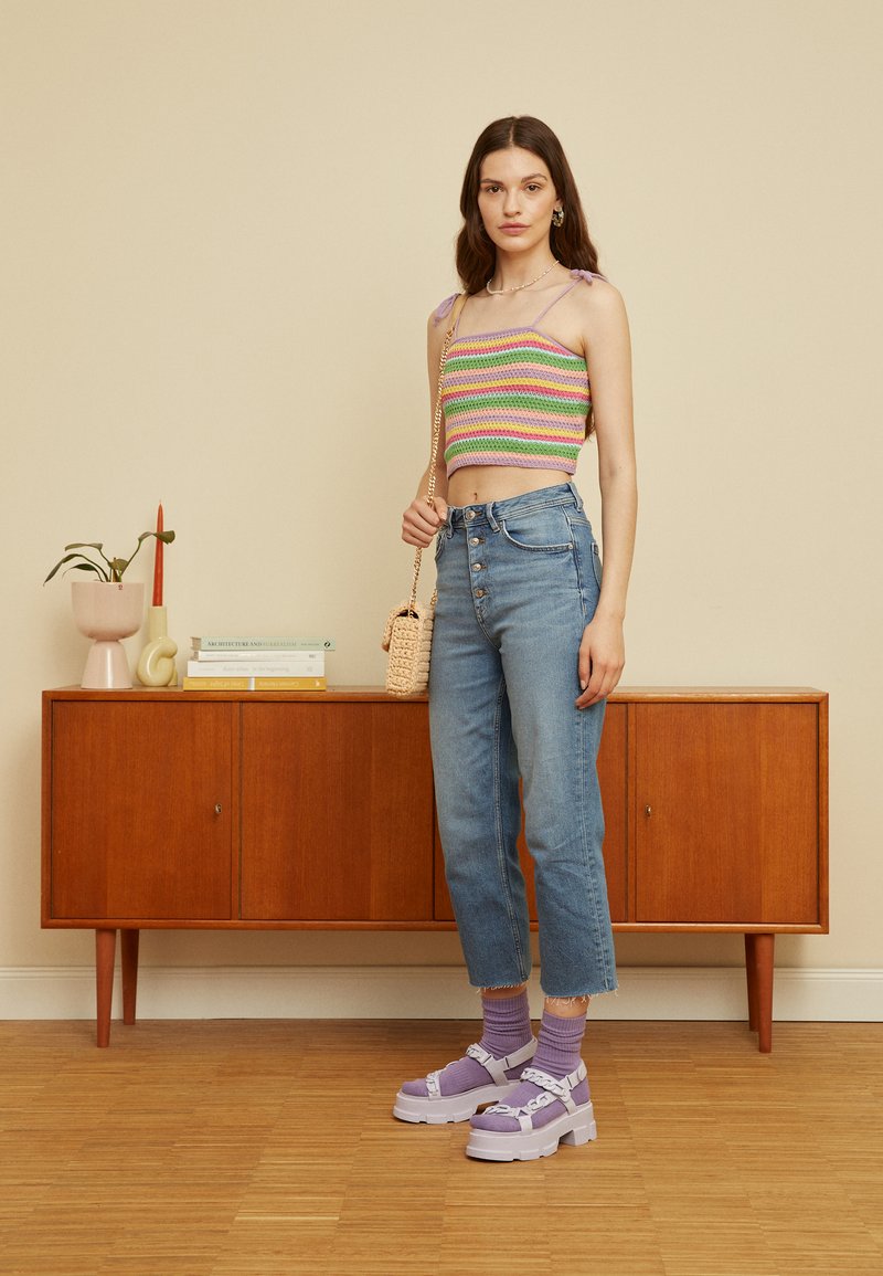 Top cropped em crochet com riscas em rosa, verde e roxo. Jeans de cintura alta em denim de lavagem clara. Sapatos chunky de plataforma em lavanda. Bolsa de trama.