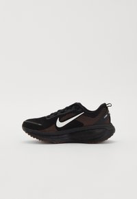Chaussure de running noire Nike avec logo swoosh blanc et accents rayés marron sur le côté, présentée sur un fond uni.