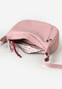 Rosa Leder Crossbody-Tasche in runder Form, mit Reißverschluss und einem gefütterten Innenraum, der eine rote Akzenttasche enthält.
