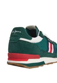 Baskets en daim vert avec des rayures blanches et rouges, lacets blancs, semelle rouge et blanche, et logo "Pepe Jeans London" sur l'onglet du talon.