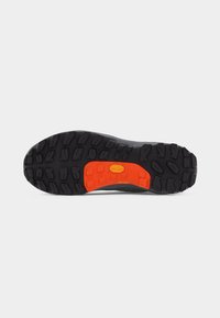 Semelle de chaussure robuste noire et orange avec des crampons profonds conçus pour offrir une traction sur diverses surfaces.