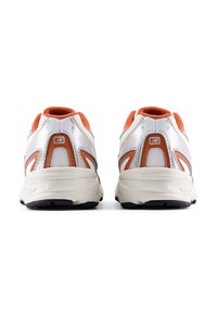 Λευκά αθλητικά παπούτσια από δίχτυ με πορτοκαλί λεπτομέρειες, διαθέτουν επένδυση στον γιακά και υφή στην σόλα. Αντανακλαστικό στοιχείο κατά μήκος των πλευρών βελτιώνει την ορατότητα.