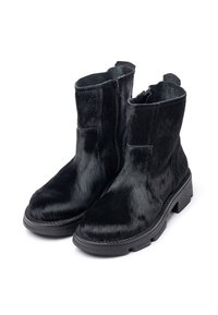 Botas negras hasta el tobillo hechas de un material similar al pelo con una textura suave, que cuentan con un zipper lateral y una suela de goma gruesa.