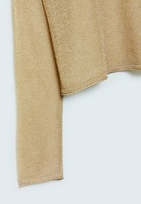 Gyllene stickad tröja med en mjuk, skimrande textur. Har en avslappnad passform och en något kortad nederkant med långa ärmar.