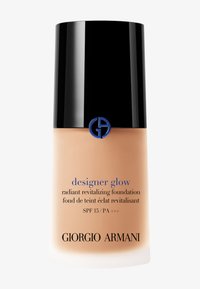 Beige vloeibare foundation in een heldere fles met een zwarte dop. Het etiket bevat blauwe en zwarte tekst; inclusief SPF 15 en "Giorgio Armani" merknaam.