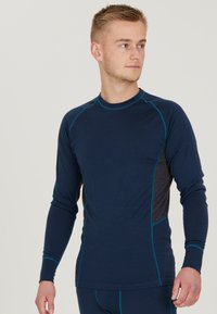 Marinblå långärmad baslagertröja med grå sidopaneler, som har kontrasterande turkosa sömmar och en rundhalsad design. Slät textur.