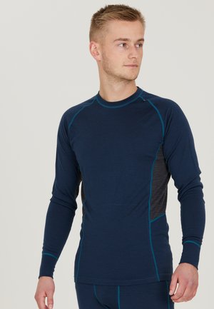 Marineblå langærmet base layer skjorte med grå sidepaneler, der har kontrasterende teal syninger og rund hals. Glat tekstur.