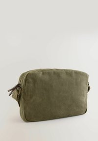 Sac en toile vert olive de forme rectangulaire, avec une fermeture éclair et des accents en cuir sur la tirette de la fermeture.