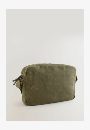 Zielona oliwkowa torba wykonana z płótna o prostokątnym kształcie, z zamkiem błyskawicznym i skórzanymi akcentami przy uchwycie zamka.