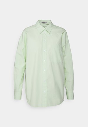 Cămașă lungă cu mânecă, de culoare verde deschis, dintr-un material moale, cu guler, un buzunar aplicat pe pieptul stâng și o croială lejeră.