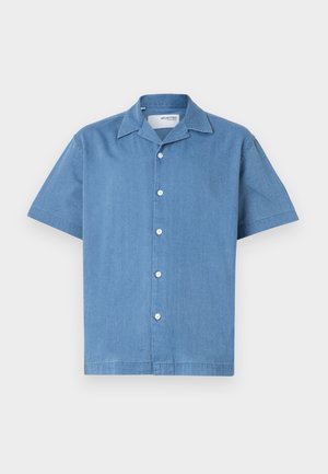 Chemise à manches courtes bleu clair en tissu doux et texturé, avec un col et cinq boutons blancs sur le devant.