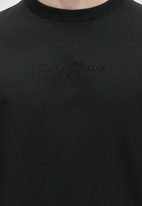 Μαύρο φούτερ με στρογγυλή λαιμόκοψη με κεντημένο κείμενο "Carlo Colucci" και "A Legacy Since 1978" στο στήθος.