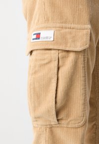Värikäs oliivinvihreä pielus, jossa on lippu ja Tommy Jeans -logopatch, joka esittää punaisia, valkoisia ja sinisiä värejä sekä tekstiä.