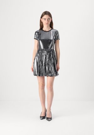 Short black sequin dress with a round neckline and short sleeves, featuring a pleated skirt. Paired with black high-heeled shoes.