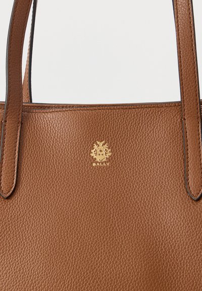 Sac cabas en cuir marron à finition texturée, doté de deux poignées et d'un logo Bally doré proéminent à l'avant.