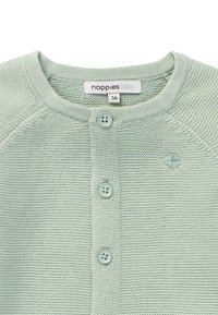 Ljusgrön stickad babykofta med rund halsringning, fyra knappar och texturerade detaljer, med en liten broderad detalj framtill.