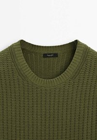 Pull en maille vert olive à col rond avec col côtelé et motif de points verticaux texturé.