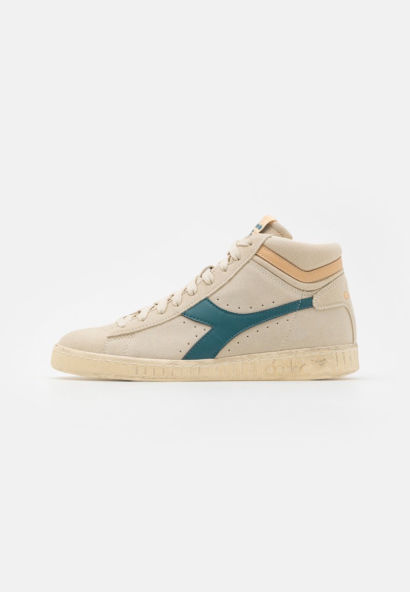 Beżowe sneakersy typu high-top z turkusem logo, wykonane z zamszu, z perferowanymi akcentami i teksturowaną gumową podeszwą. Brązowe detale przy kołnierzu.