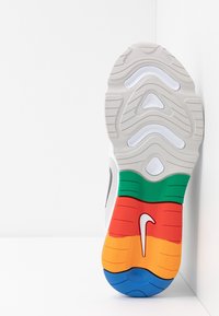 Nike-sneakersula med en texturerad vit ovandel och en färgglad gummiyttersula med sektioner i grönt, orange, rött, gult och blått.