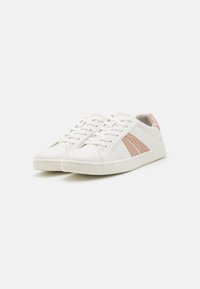 White leather sneakers with light pink glitter accents and stitched detailing. Rounded toe, laces, and textured rubber sole.