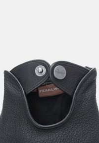 Botte en cuir noir avec une ouverture arrondie, dotée d'une fermeture à bouton et d'un intérieur doux. L'étiquette indique "PEARLWOOD." Surface texturée.