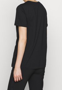 Svart bomullströja med korta ärmar och rundad halsringning. Enkelt design med rak passform och utan synliga mönster eller detaljer.