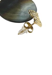 Goldfarbige Ohrringe mit filigranen Details, ausgestattet mit einem transparenten Silikonrücken, vor einer dunklen, runden Oberfläche.