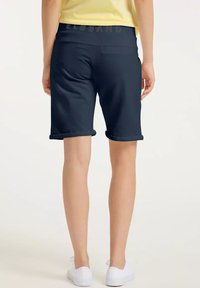 Navy blue shorts with a rolled hem and a textured waistband featuring the brand name. Smooth fabric and mid-thigh length design.