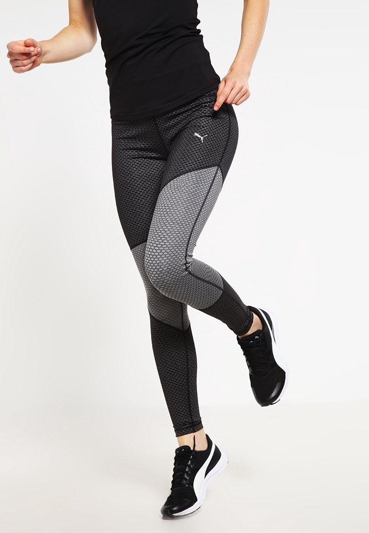Zwarte en grijze patroon sportlegging met meshpanelen en een getailleerd ontwerp. Gecombineerd met zwarte sportschoenen met een witte zool.