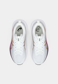 Witte sportieve schoenen met een ademend bovenwerk van mesh, oranje accenten en een paarse zool. Beschikt over traditionele veters en gestructureerde patronen.