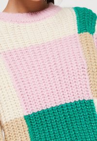 Sweter dziany z teksturowanym wzorem w blokach w odcieniach różu, kremu, beżu i zieleni. Okrągły dekolt z prążkowanym wykończeniem.