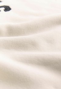 Tela de algodón blanca con una textura suave, que presenta ligeras arrugas y una superficie lisa. Diseño minimalista, centrado en la calidad del material.