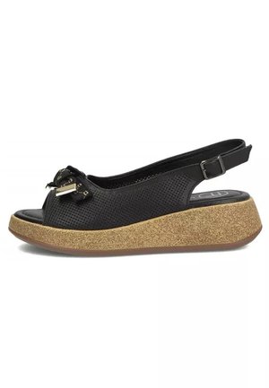 Czarna perforowana sandałka na koturnie z odkrytymi palcami, ozdobną kokardką i złotym akcentem oraz podeszwą na platformie o fakturze korka.