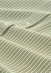 Tessuto verde chiaro con stretti righe diagonali marroni, con bottoni lungo un bordo; texture liscia e design piegato.