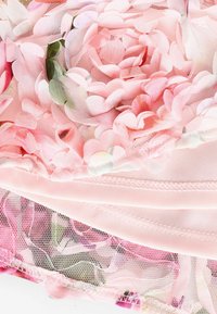 Blumiger Stoff mit geschichteten rosa Netzblütenblättern und grünen Akzenten. Die Basis ist sanft rosa mit sichtbaren Nähten und einem netzartigen Überzug.