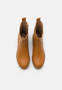 Bottes chelsea marron clair avec une finition lisse et des panneaux latéraux élastiques, vues de dessus sur un fond blanc.
