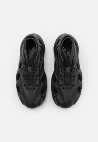 Svarta träningsskor med en texturerad ovandel och urklippta mönster, snörning framtill och vadderad krage för komfort.