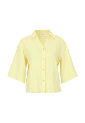 Krátký rukáv, košile na knoflíky ze světle žlutého lnu s límečkem a přední légou. Má široké rukávy a uvolněný střih.