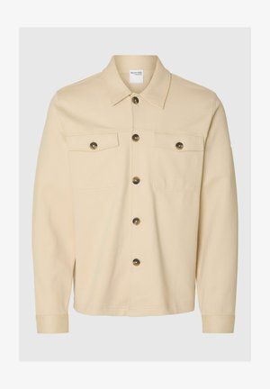 Šviesiai rudas mygtukinis švarkas su apykakle, dviem krūtinės kišenėmis ir tamsiais mygtukais. Pagamintas iš tekstūruoto audinio, turi ilgus rankovės ir tiesų apatinį kraštą.