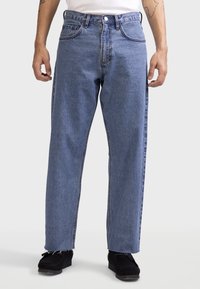 Lichtblauwe spijkerbroek met een recht model, zichtbare stiksels, vijf zakken en rafelige zoomdetails. Verstelbare tailleband met knoopsluiting.