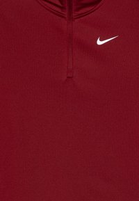 Piros, hosszú ujjas felső, negyed cipzárral, sima anyagból készült. Elöl fehér Nike logó található.