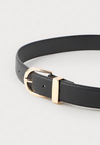 Schwarzer Ledergürtel mit goldener, runder Metallschnalle und rechteckigem Halter auf einem weißen Hintergrund.