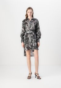 Abito camicia in una fantasia astratta nera e grigia, con colletto, maniche lunghe dalla forma a sbuffo e vita cinturata.