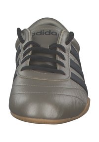 Chaussure en cuir gris avec des accents rayés noirs et des lacets plats. Dotée d'un bout rond et d'une surface texturée, adaptée à une utilisation en intérieur.