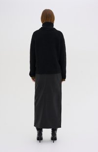 Wool turtleneck nera con finitura testurizzata, abbinata a una gonna maxi in pelle nera con dettagli cuciti e stivali con tacco neri.