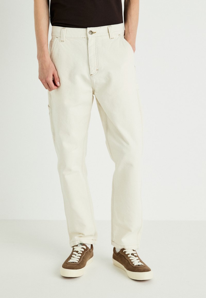 Beige cargo pants with a relaxed fit, button closure, and multiple pockets. Made of sturdy cotton fabric, featuring subtle stitching details.