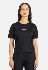 Camiseta de algodón negra con mangas cortas, cuello redondo y ajuste cropped. Presenta un logotipo en blanco de "ROSSIGNOL" en el frontal. Textura suave.