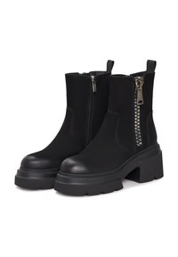 Stivaletti neri realizzati in pelle liscia con zip laterale e dettagli metallici, e un tacco a pianta robusta. Dettagli testurizzati sulla zip.